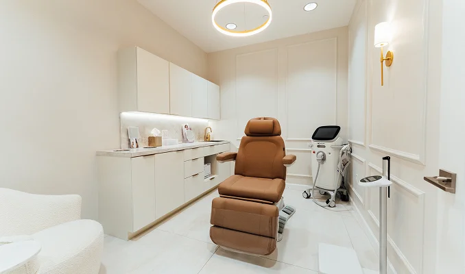 Modern minimalist medical spa treatment room with brown leather chair, white cabinets and clean aesthetic - locations in New York, NY