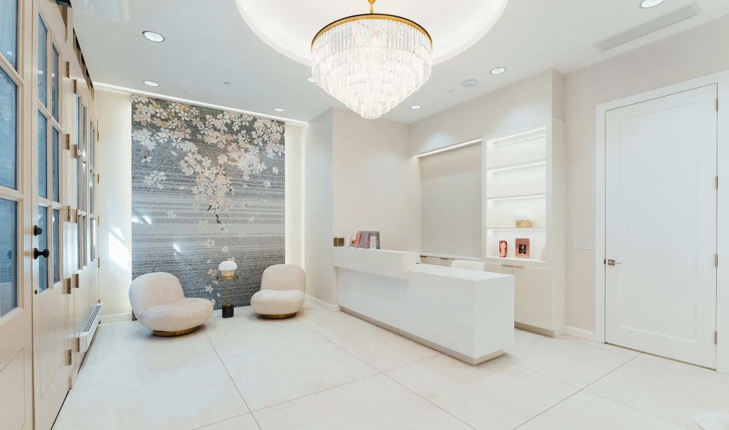 Modern white minimalist office reception area with elegant chandelier and contemporary furniture - Location in New York, NY