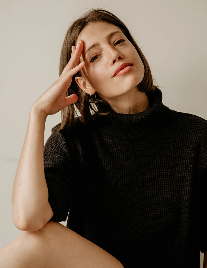 Woman in black turtleneck sweater posing with hand near face in natural lighting portrait - Aveli in New York, NY