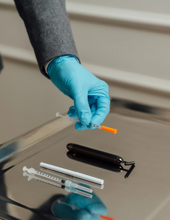 Healthcare worker holding syringe and vial for vaccine preparation with medical supplies on table - dermal fillers in New York, NY