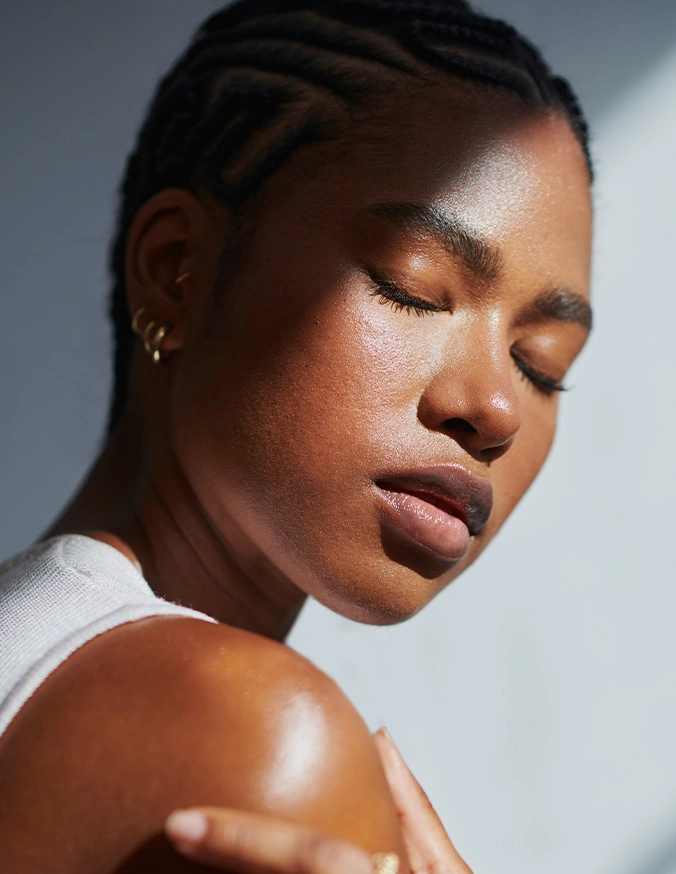 Black woman with glowing skin and closed eyes in natural light, showcasing healthy skincare and beauty routine - earlobe repair in New York, NY