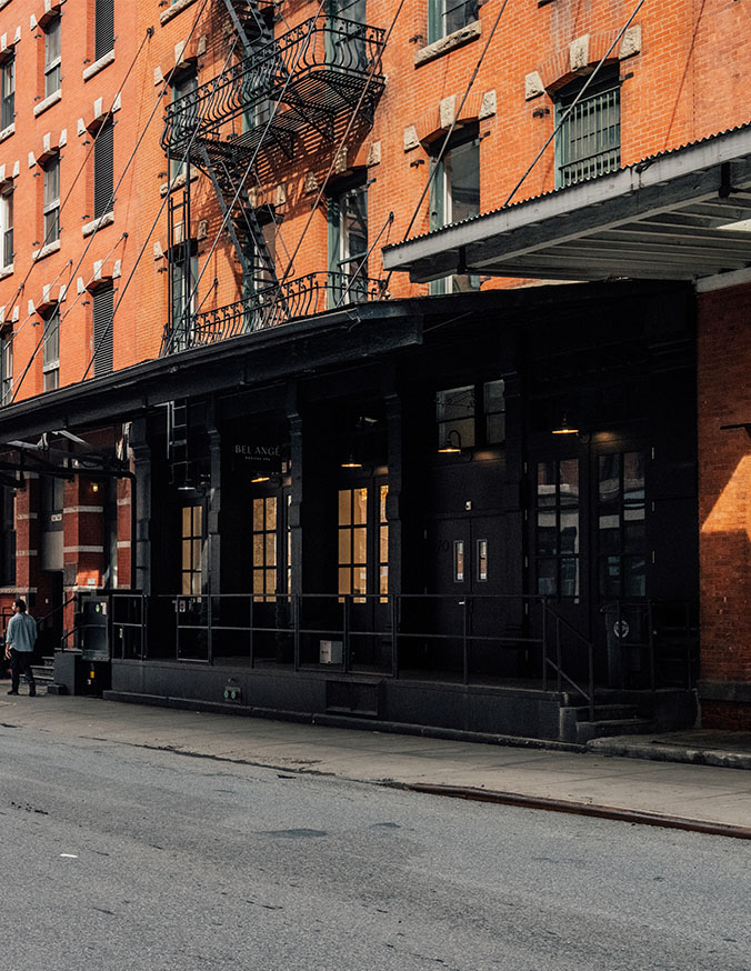 Black storefront with orange brick building in urban neighborhood street scene - in New York, NY