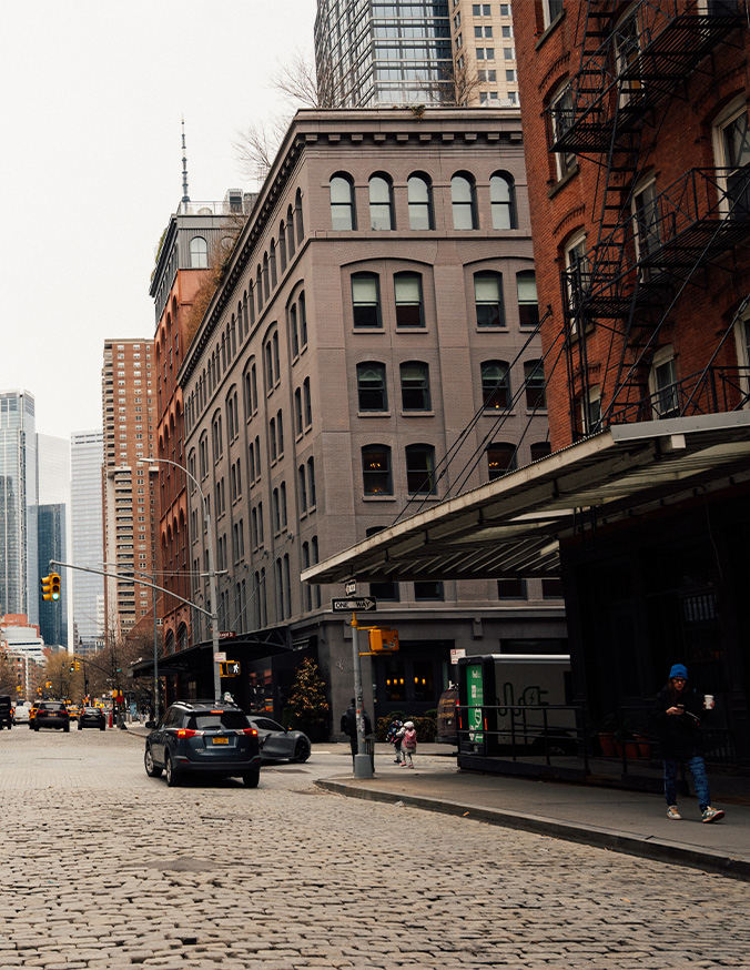 Historic cobblestone street with classic brick buildings in urban downtown district showing multiple business locations - in New York, NY