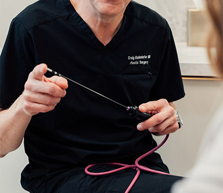 Dr Craig Baldenhofer MD demonstrating suturing technique with surgical instruments and pink practice thread - in New York, NY