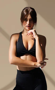 Woman in black athletic wear posing confidently against neutral background in fitness apparel - new breast implant in New York, NY