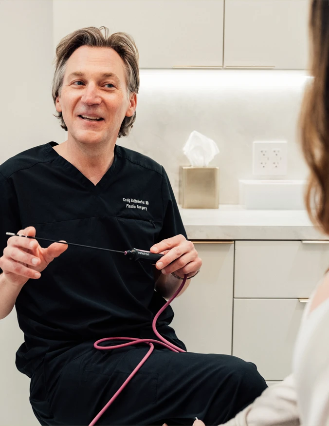 Dr Craig Baldenhofer MD consulting with patient about body contouring procedures after weight loss in medical office - in New York, NY